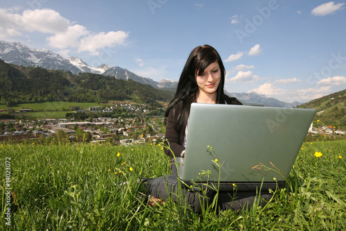 Foto: Mädchen mit Laptop in Wiese / Hintergrund Schladming Mädchen mit Laptop in Wiese / Hintergrund Schladming