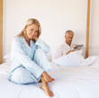 Beautiful mature blond sitting on bed with her husband