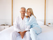 Romantic mature couple sitting on the bed in their apartment