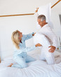 Pillow fight: Happy mature couple enjoying themselves