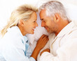 Mature couple holding hands on bed