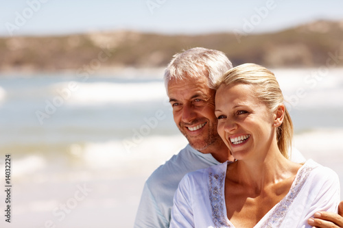 Foto: Happy mature couple embracing on a sunny day at the beach Happy mature couple embracing on a sunny day at the beach