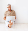 Mature man working on the laptop while sitting on the floor