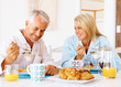 Happy old couple having breakfast at the table