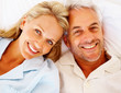Closeup of a smiling senior couple lying on bed, head to head