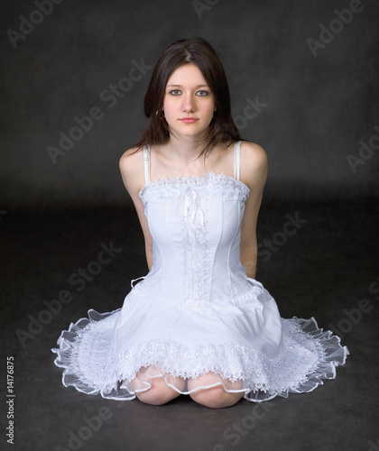 Photo: Girl in a white dress sits on a black background Girl in a white dress sits on a black background