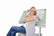 Woman sitting by blue prints on drafting board, smiling portrait, cut out