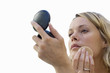 young woman applying makeup, looking in mirror, cut out