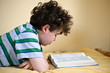 Boy reading book lying on bed