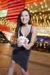 Photo: Portrait of young woman holding playing cards in front of illuminated casino, Las Vegas, Nevada, USA Portrait of young woman holding playing cards in front of illuminated casino, Las Vegas, Nevada, USA