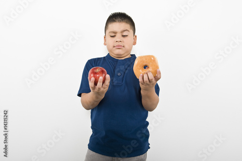 Photo: Pre-teen 10-12 boy holding doughnut and apple Pre-teen 10-12 boy holding doughnut and apple