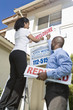 Two people putting up notice outside house