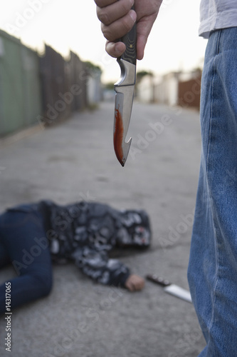 Photo: Man standing next to stabbed man lying on ground Man standing next to stabbed man lying on ground