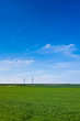 canvas print picture Wind turbines farm in green field over cloudy sky