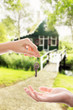 Handing over house key with a new home in the background Handing over house key with a new home in the background