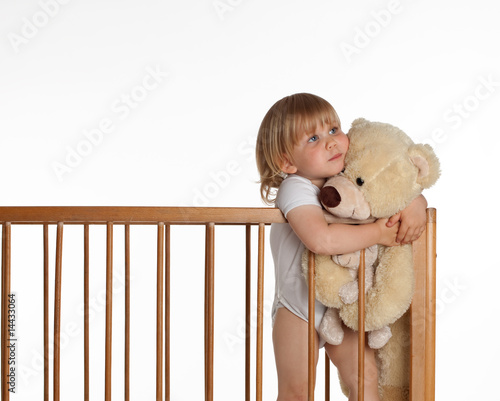 Photo: portrait of little girl keeping teddybears in crib portrait of little girl keeping teddybears in crib