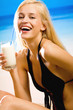 Young beautiful smiling woman with milkshake on beach