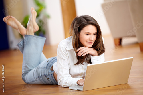 Photo: Junge Frau mit Laptop am Boden liegend Junge Frau mit Laptop am Boden liegend