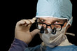 Surgeon looks over magnifying glasses Surgeon looks over magnifying glasses