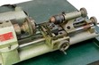 Small portable metal lathe on green board isolated closeup