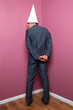 Businessman standing in the corner in a dunce hat