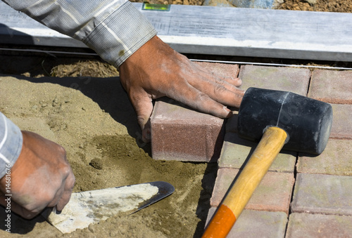 Photo: The worker stacks road from a square tile The worker stacks road from a square tile