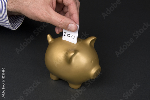 Photo: Placing IOU slip into piggy bank Placing IOU slip into piggy bank