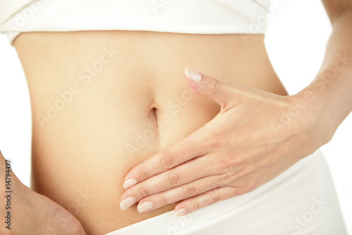 Photo: Closeup of young woman with hand on her stomach Closeup of young woman with hand on her stomach