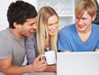 Happy friends using a laptop in the kitchen