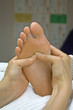 Reflexologist working the diaphragm area on woman's foot