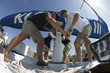 Sailors operating windlass on yacht, low angle view