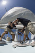 Sailors operating windlass on yacht, low angle view, wide angle lens