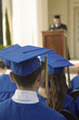 Graduates listening to speaker outside, back view