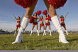 Cheerleader in white knee high boots, low section with cheerleaders behind