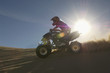 Man riding quad bike in desert against sun