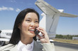 Photo: Smiling Businesswoman standing outside Airplane, talking on mobile Smiling Businesswoman standing outside Airplane, talking on mobile