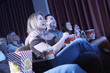 Smiling Couple sitting, arms around, Watching Movie in theatre