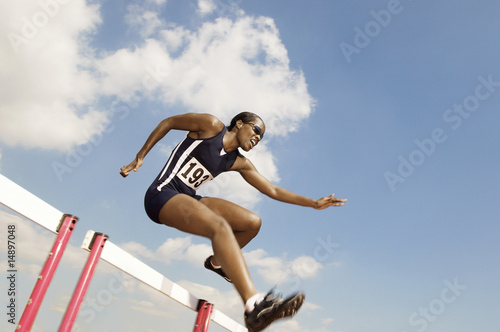 Photo: Female athlete jumping hurdle Female athlete jumping hurdle