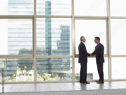 Photo: Businessmen shaking hands in office building Businessmen shaking hands in office building