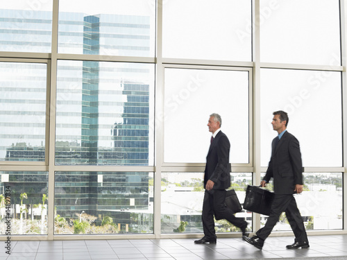 Photo: Businessman walking by office window Businessman walking by office window