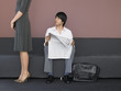 Businesswoman and Businessman Reading Newspaper in Lobby