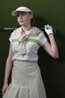 Woman in visor holding golf club behind shoulders, portrait
