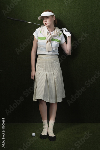 Photo: Woman in visor holding golf club behind shoulders, portrait Woman in visor holding golf club behind shoulders, portrait