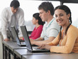 Row of teenage students using laptops in classroom