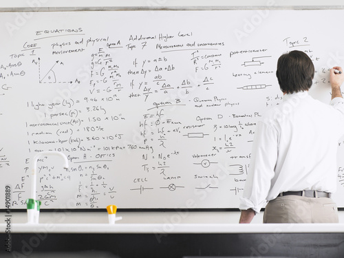 Photo: Teacher writing on whiteboard, back view Teacher writing on whiteboard, back view