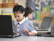 Elementary schoolgirl using laptop in classroom