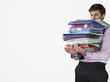 Male office worker carrying heavy binders, on white background
