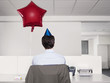 Man celebrating birthday, working alone in office