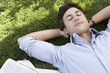 Man lying on grass by newspaper, close up, elevated view