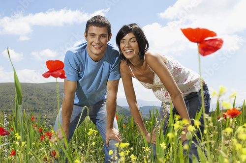 Photo: Young couple standing in mountain meadow, portrait, front view Young couple standing in mountain meadow, portrait, front view